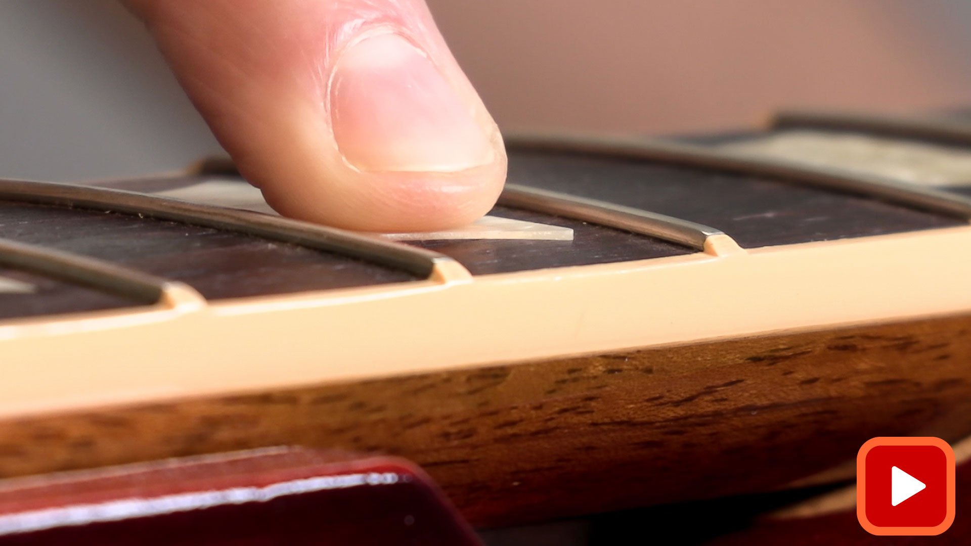 Finger showing inlay raised above fingerboard
